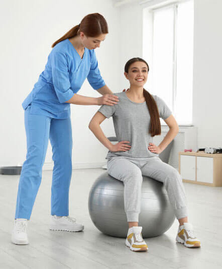 Physiotherapist assisting patient on a ball